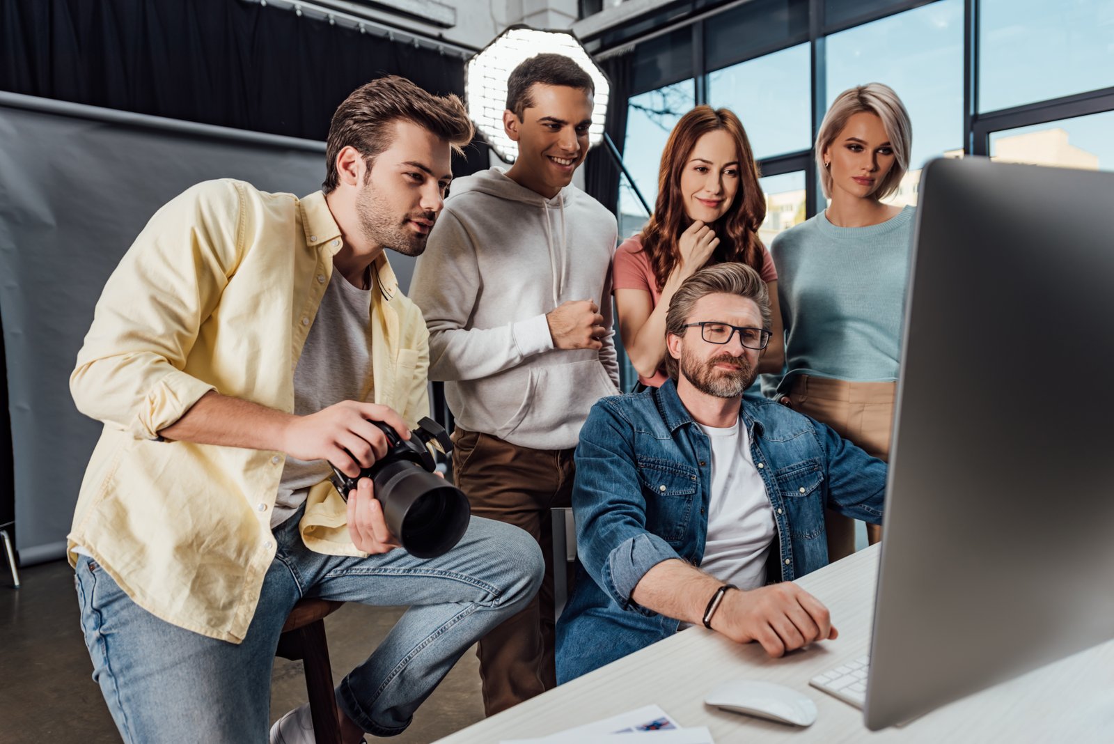 A creative team reviews photos on a computer in a studio.