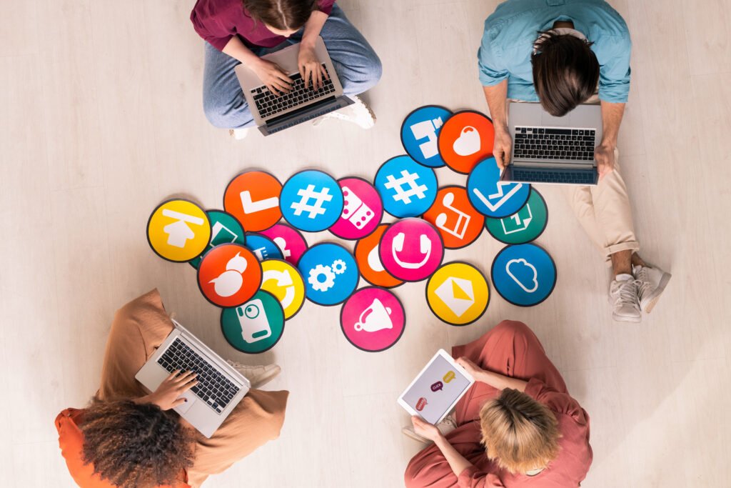 Young professionals collaborating on laptops and tablets, surrounded by colorful icons symbolizing digital tools and services, highlighting teamwork and innovation in digital marketing services in Kochi