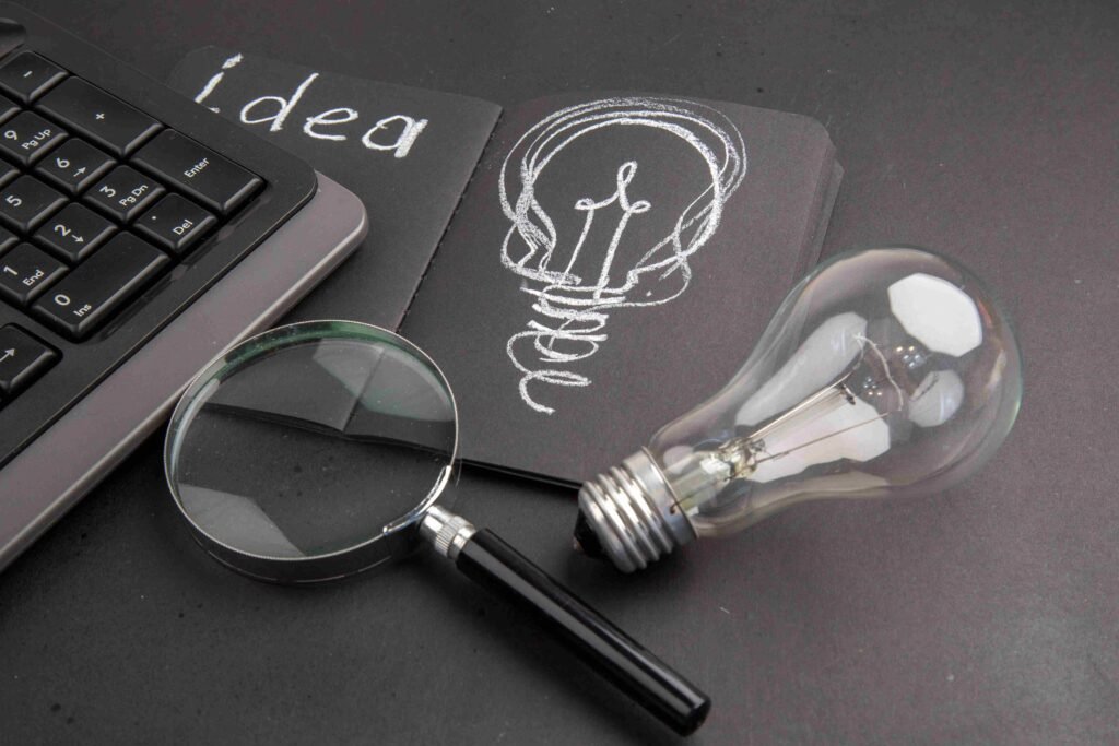 A light bulb, magnifying glass, and idea sketch on a notebook. - Marketing and Digital Marketing Services