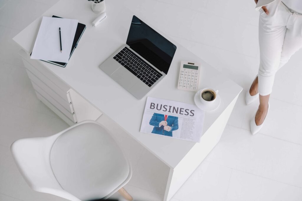 A modern white office desk with a laptop, documents