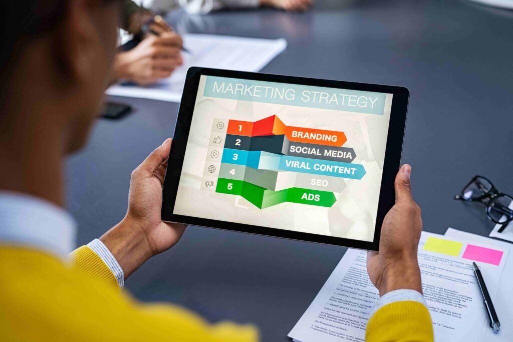 A person holding a tablet displaying a marketing strategy with five key elements - Marketing and Digital Marketing Services