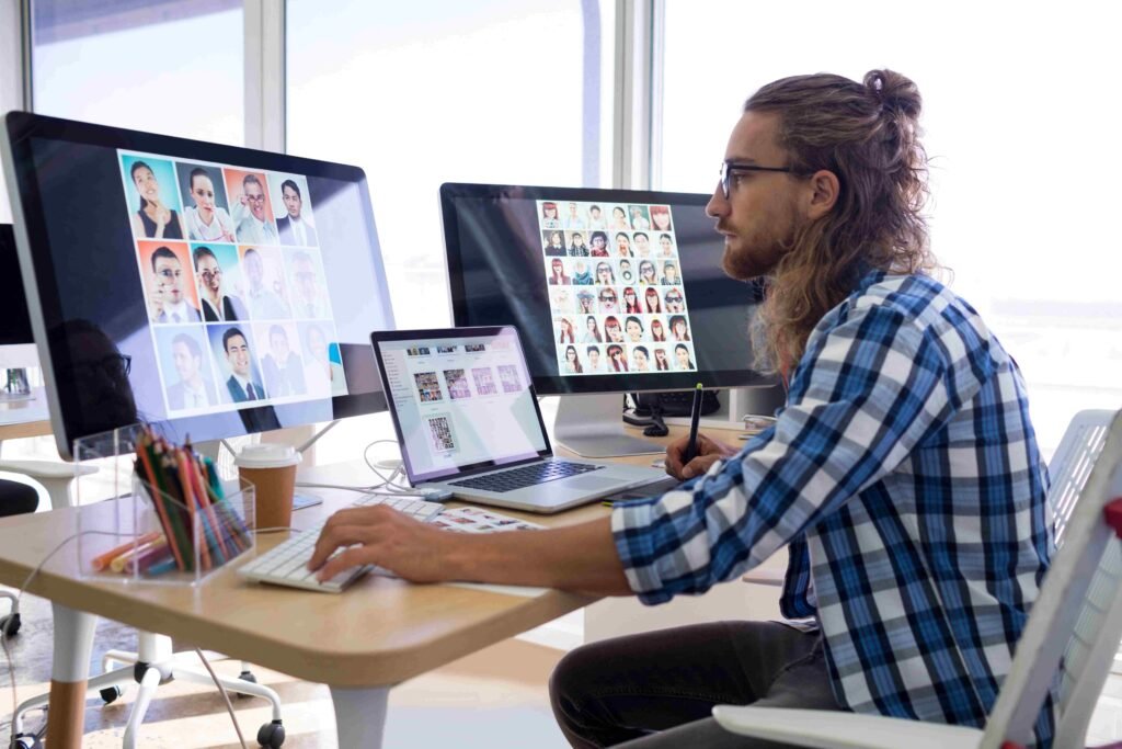 This image shows a professional working at a modern office setup with multiple monitors