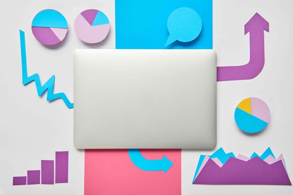 A closed laptop on a desk with colorful paper charts. - Marketing and Digital Marketing Services